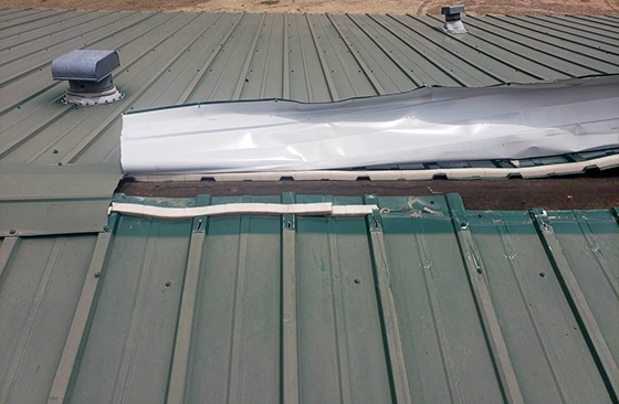 Metal roof panel peeled back and curled by storm winds