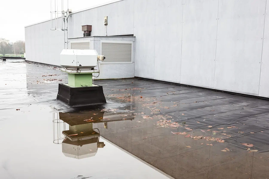 Ponding water pooling around a rooftop vent on a flat commercial roof