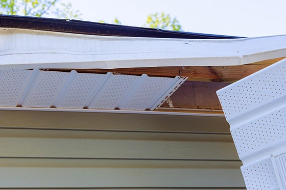 Damaged soffit panel pulled loose from a roof overhang after a storm