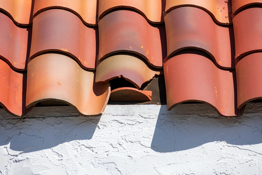 Cracked and broken barrel tiles on a storm-damaged tile roof