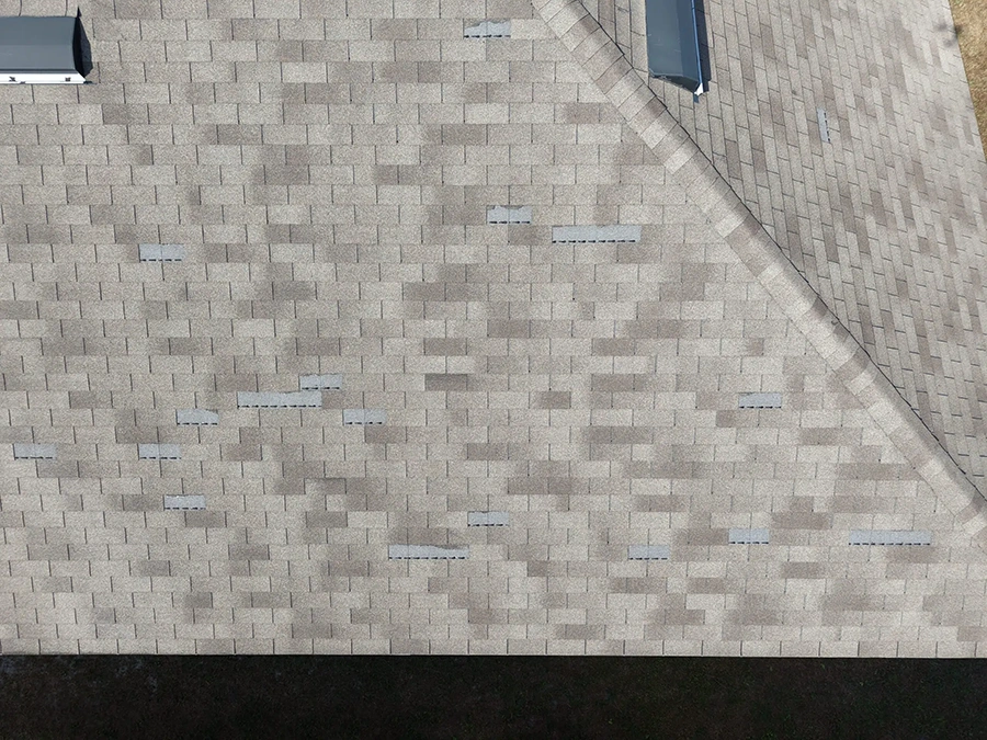 Aerial view of asphalt shingle roof repairs with replacement shingles patched across the slope