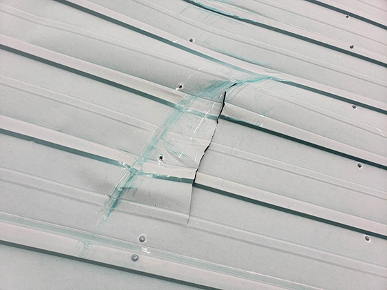 Cracked seam and sealant failure on a metal roof panel