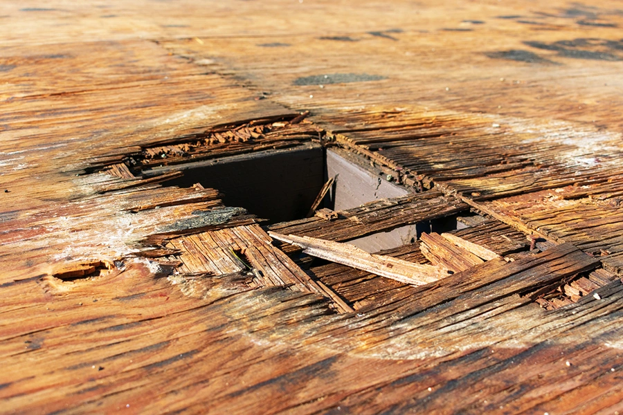 Hole torn through a roof exposing rotted decking and rafters