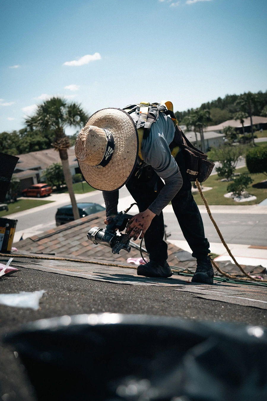 Roofer using a nail gun during a residential roof replacement on a Florida home