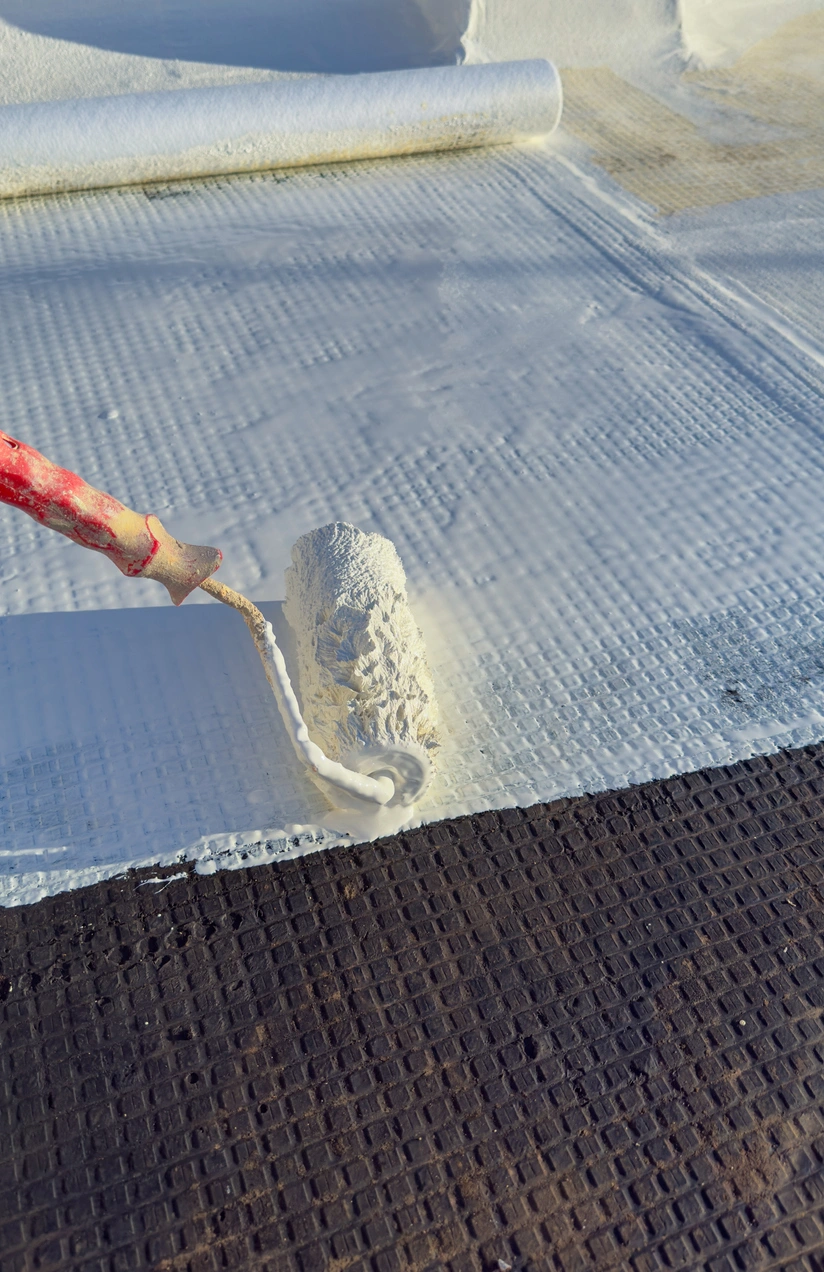 Protective roof coating being rolled onto a membrane roof surface