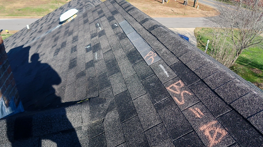 Chalk inspection markings on a storm-damaged shingle roof slope