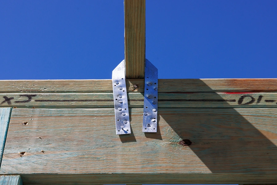 Hurricane strap connector securing a roof truss to the wall framing
