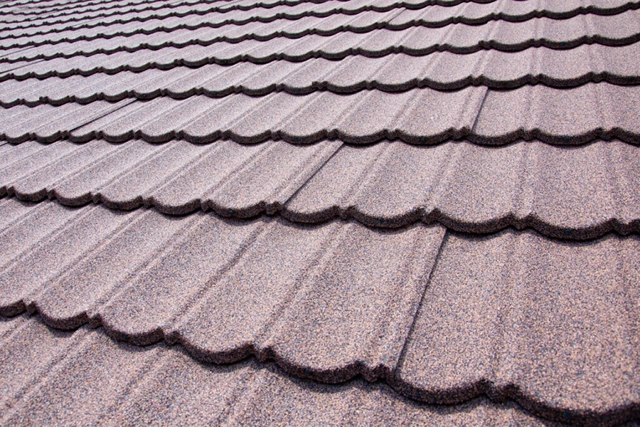 Close-up of textured stone-coated steel roofing tiles in a scalloped profile