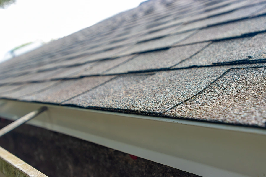 Asphalt shingle roof edge meeting the gutter line on a home
