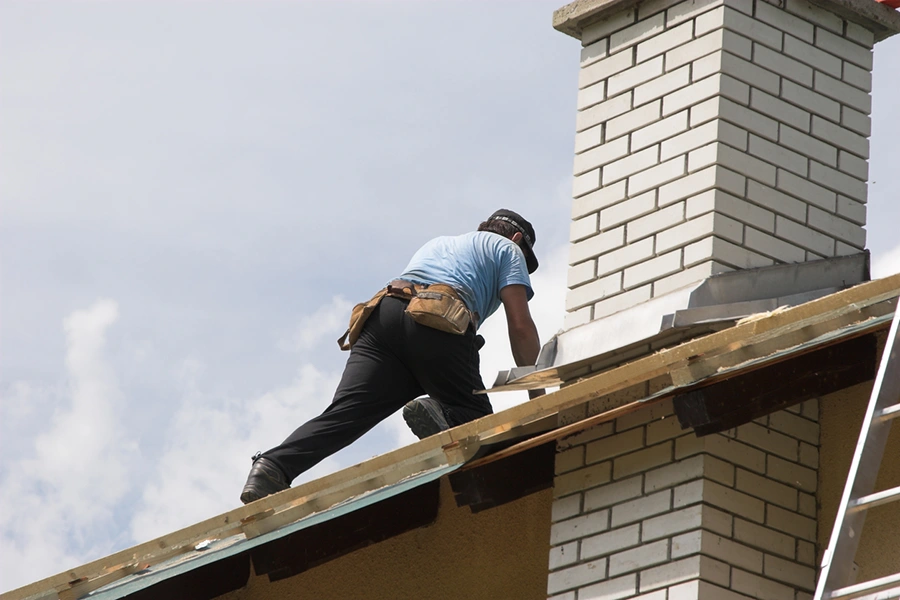Roofer working alongside a chimney during a roof upgrade