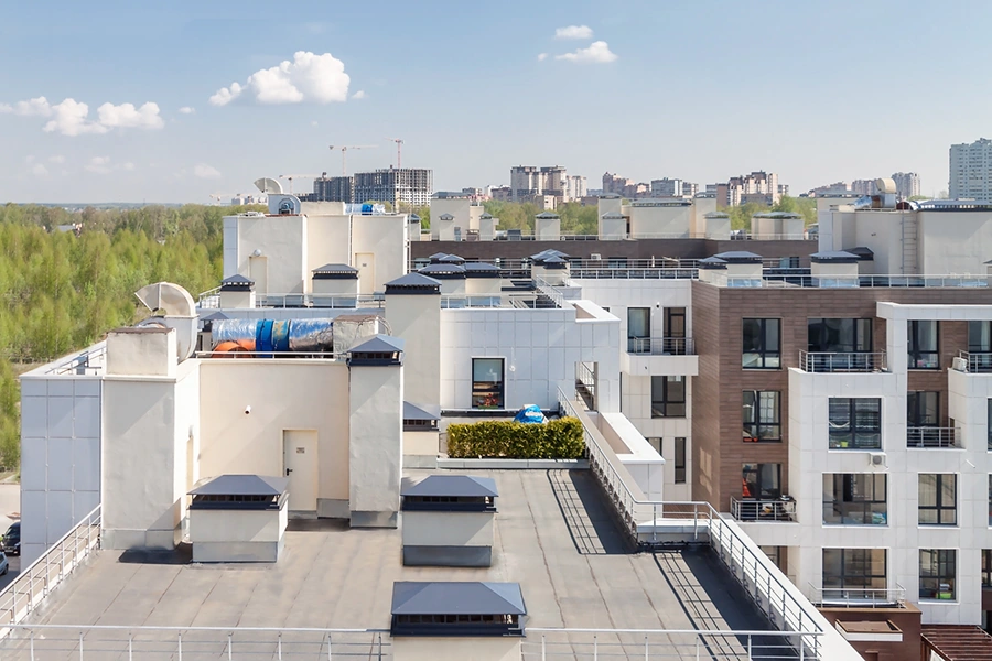 Flat roof with air conditioners on top of a modern apartment complex building exterior
