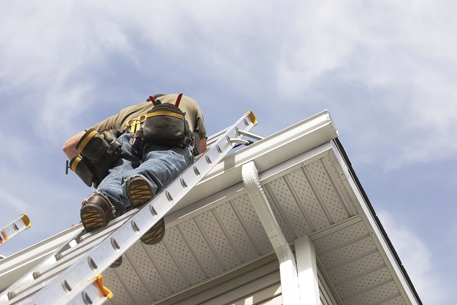 Roofer up a ladder repairing a gutter