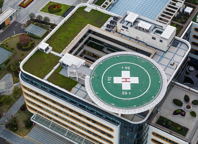 Aerial view of a medical facility roof with a helipad and rooftop green space