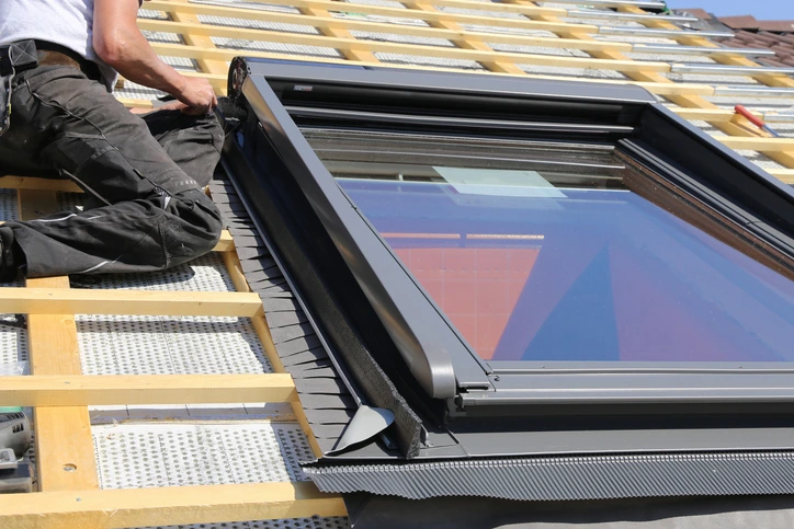 Roofer installing a new skylight on a residential roof, with battens and underlayment in place during installation