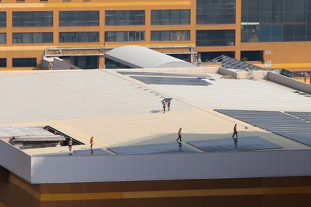 Workers walking across a large flat retail building roof with rooftop solar panels