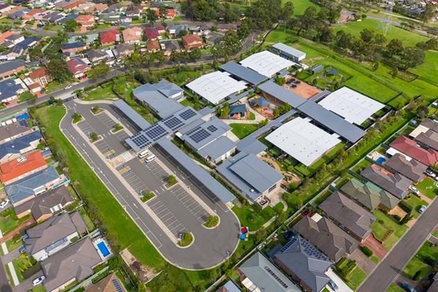 Aerial view of a school campus with white metal roofing across multiple classroom buildings