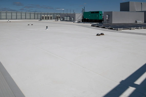 White PVC membrane roof on a commercial building alongside rooftop solar panels